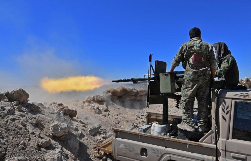 A fighter with the Syrian Democratic Forces (SDF) fires a truck-mounted gun toward a part of Baghouz where remaining Islamic State (IS) group fighters are holding out in their last position, in the countryside of the eastern Syrian province of Deir Ezzor on March 18, 2019. - A shroud of black smoke covered the Islamic State group's last Syria redoubt today as US-backed forces battled holdout jihadists after a night of shelling and heavy air strikes. The Kurdish-led SDF have been closing in on IS fighters holed up in a small sliver of territory in the village of Baghouz in eastern Syria since January. (Photo by GIUSEPPE CACACE / AFP)