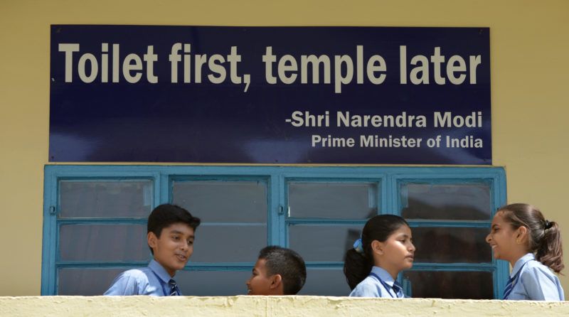 TO GO WITH India-sanitation-social-toilet-Gandhi,FOCUS BY ABHAYA SRIVASTAVA In this photograph taken on September 22, 2014, Indian schoolchildren talk in front of a poster bearing a quote from Prime Minister Narendra Modi at a school run by sanitation charity Sulabh International in New Delhi. Surrounded by latrines and soap dispensers, charity founder Bindeshwar Pathak is most at home in the toilet, one of which he vows to build in every impoverished home in India. AFP PHOTO/SAJJAD HUSSAIN (Photo by SAJJAD HUSSAIN / AFP)