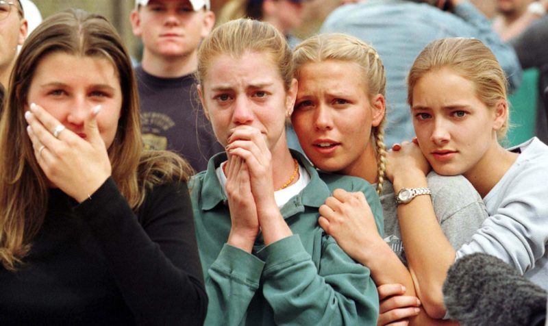 Students from Columbine High School in Littleton, CO watch as the last of their fellow students are evacuated from the school building 20 April 1999 following a shooting spree at the school, which police feared killed as many as 25 people. Two masked teens stormed their school and blasted fellow students with guns and explosives before turning their weapons on themselves in the rampage. AFP PHOTO Mark LEFFINGWELL (Photo by MARK LEFFINGWELL / BOULDER DAILY CAMERA / AFP)