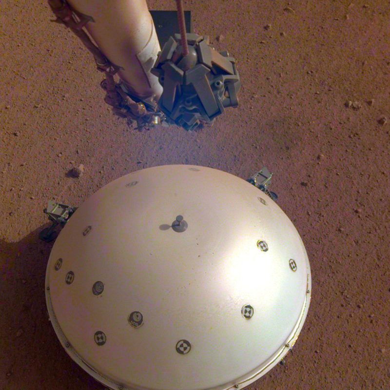 Világûr, 2019. április 24. Az amerikai Országos Repülésügyi és Ûrkutatási Hivatal, a NASA által 2019. április 23-án közreadott kép a NASA InSight nevû Mars-szondájának hõpajzzsal védett szeizmométerérõl. A francia ûrkutatási ügynökség, a Cnes közleménye szerint április 6-án gyenge, de világosan észlelhetõ rengést érzékelt a Marson az amerikai ûrszonda. A Mars belsejének kutatása céljából május 5-én útjára indított InSight robotgeológus ûrszonda mintegy 485 ezer kilométernyi út megtétele után 2018. november 26-án landolt a vörös bolygón. MTI/AP