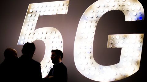 --FILE--Visitors talk in front of a logo of 5G during the Mobile World Congress 2019 (MWC19) in Barcelona, Spain, 26 February 2019. Fifth-generation wireless network, or 5G, is expected to directly create more than three million jobs in China by 2025, according to a white paper on the development of the country's digital economy from the China Academy of Information and Communications Technology.