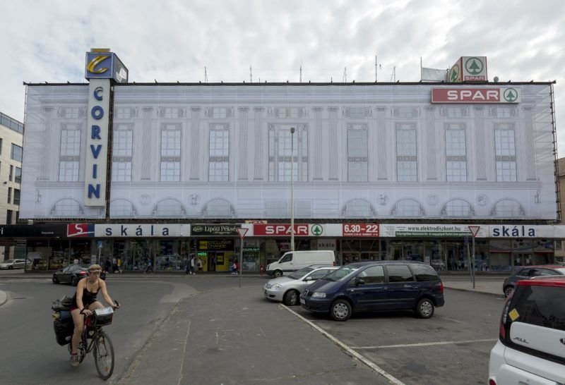 Budapest, 2018. június 18. Az épület eredeti homlokzatát mintázó háló fedi a felújítás alatt álló Corvin áruház köré felállított állványzatot a fõvárosi Blaha Lujza téren 2018. június 18-án. MTI Fotó: Mohai Balázs