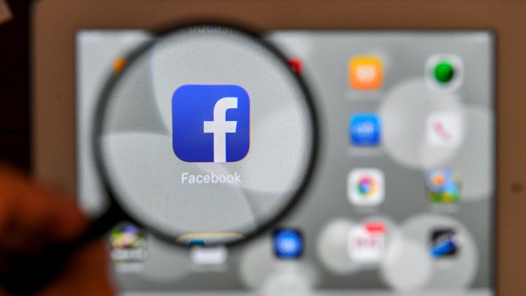 A tablet screen displays the logo of the social networking site Facebook through a magnifying glass, in Bogota, on March 22, 2018. A public apology by Facebook chief Mark Zuckerberg on March 22 failed to quell outrage over the hijacking of personal data from millions of people, as critics demanded the social media giant go much further to protect privacy. / AFP PHOTO / Luis ACOSTA