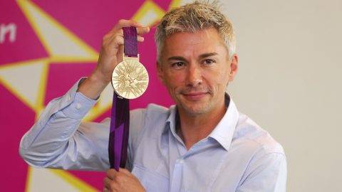 - EDITORS NOTE - RESTRICTED TO EDITORIAL USE - MANDATORY CREDIT AFP PHOTO / LOCOG / HO - NO MARKETING - NO ADVERTISING CAMPAIGNS - DISTRIBUTED AS A SERVICE TO CLIENT - A handout image obtained from the London 2012 organising committee (LOCOG) on July 27, 2011 shows British triple jump Olympic gold medallist Jonathan Edwards posing with the London 2012 Olympic gold medal. The Olympic medals circular form is a metaphor for the world. The front of the medal always depicts the same imagery at the summer Games, the Greek Goddess of Victory, Nike, stepping out of the depiction of the Parthenon to arrive in the host city. The design for the reverse of the London 2012 Olympic medals contains five main symbolic elements: the dished background suggests a bowl similar to the design of an amphitheatre, the core emblem is an architectural expression, a metaphor for the modern City, the grid brings both a pulling together and sense of outreach on the design - an image of radiating energy that represents the athletes achievements and effort, the River Thames is a symbol for London and the square is the final balancing motif of the design, opposing the overall circularity of the design and emphasising its focus on the centre and reinforcing the sense of place as in a map inset. AFP PHOTO / LOCOG/ HO ATTENTION - EMBARGO, RELEASABLE Wednesday July 27, 2011 at 1830 GMT - THIS RESTRICTION APPLIES TO ALL MEDIA INCLUDING WEBSITES ---- EDITORS NOTE ---- RESTRICTED TO EDITORIAL USE - MANDATORY CREDIT *AFP PHOTO / LOCOG/ HO* - NO MARKETING NO ADVERTISING CAMPAIGNS - DISTRIBUTED AS A SERVICE TO CLIENTS / AFP PHOTO / LOCOG / -