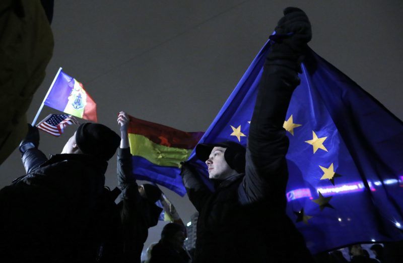 Bukarest, 2018. február 22. Román és EU-zászlót tartanak demonstrálók a bukaresti kormánypalota elõtti téren 2018. február 22-én este, miután Tudorel Toader igazságügyi miniszter bejelentette, hogy kezdeményezi Laura Codruta Kövesi, a román korrupcióellenes ügyészség (DNA) vezetõjének elmozdítását. A tüntetõk a korrupcióellenes harc folytatását, az igazságügyi miniszter és az egész kormány lemondását követelték. Klaus Iohannis román államfõ védelmébe vette Laura Codruta Kövesit. (MTI/EPA/Robert Ghement)