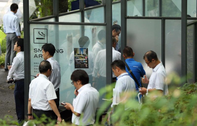 Office workers gather at a smoking area at noon in Shinjuku Ward, Tokyo on July 1, 2019. In Japan, public facilities such as school and hospital became completely non-smoking since the same day. In addition, people will not be able to smoke outside except where there is a sign indicating that people can smoke. From next April, restaurant and hotel will become non-smoking at s as well. ( The Yomiuri Shimbun )