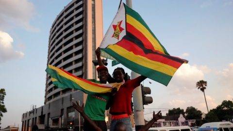 People and soldiers celebrate after the resignation of Zimbabwe's president Robert Mugabe on November 21, 2017 in Harare. Car horns blared and cheering crowds raced through the streets of the Zimbabwean capital Harare as news spread that President Robert Mugabe, 93, had resigned after 37 years in power. / AFP PHOTO / Marco Longari