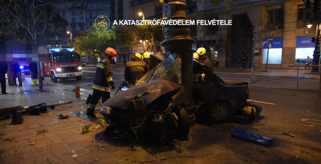 Videón, ahogy a katasztrófavédelem küszködik a Károly körúton oszlopra csavarodott autó roncsával