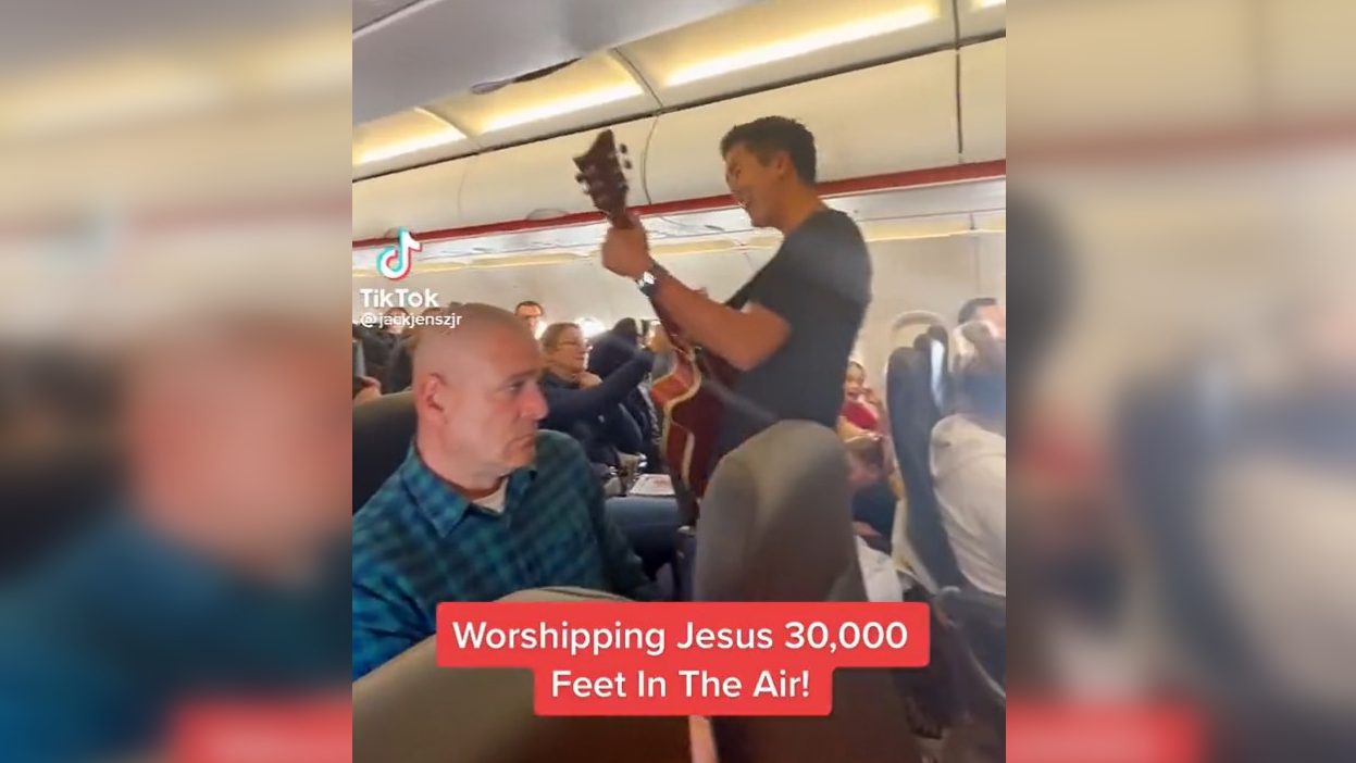 Videón, ahogy az égben, egy utasokkal teli gépen dicsőíti Jézust egy gitárral és a híveivel egy lelkész