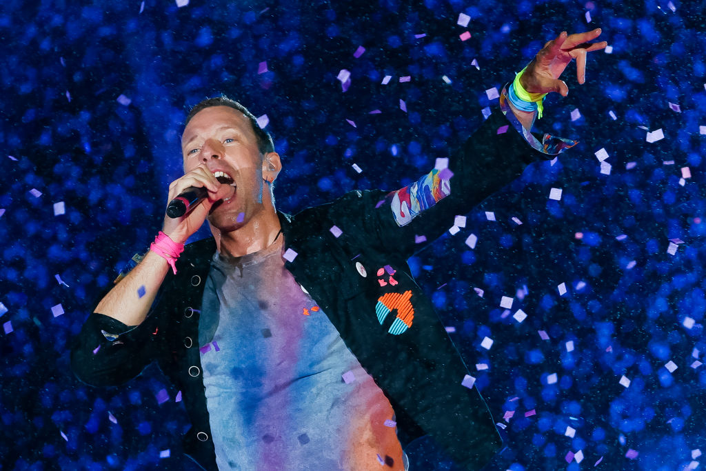 Videó! Chris Martin álruhában énekelt egy karaoke bárban – egy túlméretezett zakóban, parókával, szemüvegben állt ki